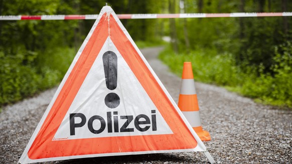 Ein gesperrter Waldweg mit einem Absperrband und einem Warndreieck mit der Aufschrift Polizei im Huerstwald, am Donnerstag, 5. Mai 2022 in Zuerich. Die Kantonspolizei Zuerich sperrte den Huerstwald im ...