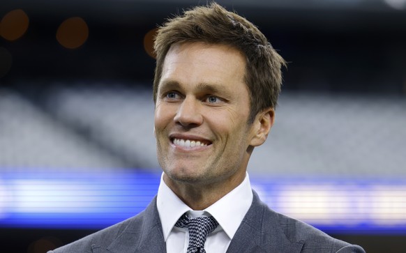 Fox Sports lead NFL analyst Tom Brady stands on the field during warmups before an NFL football game between the Detroit Lions and the Dallas Cowboys in Arlington, Texas, Sunday, Oct. 13, 2024. (AP Ph ...