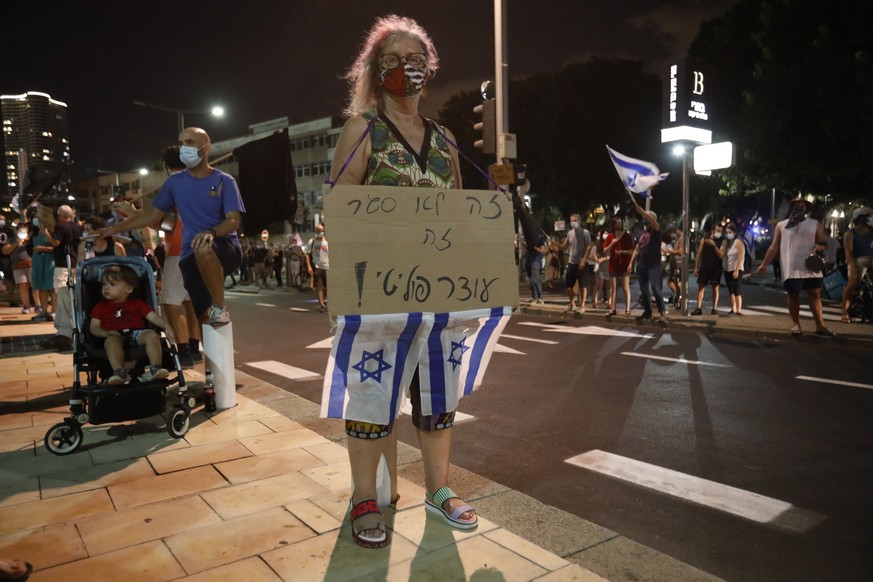 An Israeli protester holds a banner saying &quot;it not a lockdown its a political curfew&quot; during a demonstration against lockdown measures that protesters believe are aimed at curbing protests a ...