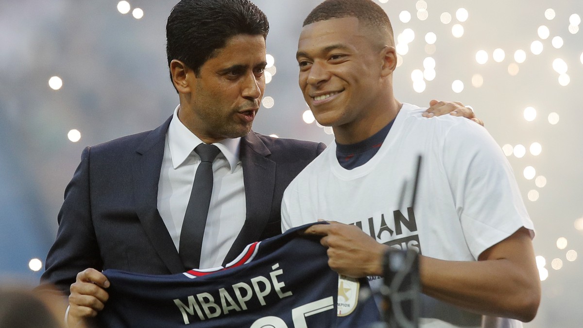 PSG President Nasser Al-Khelaifi, left, speaks to PSG's Kylian Mbappe who holds a shirt with his name and 2025 on it as it is announced he has signed a three year extension to his contract on the ...