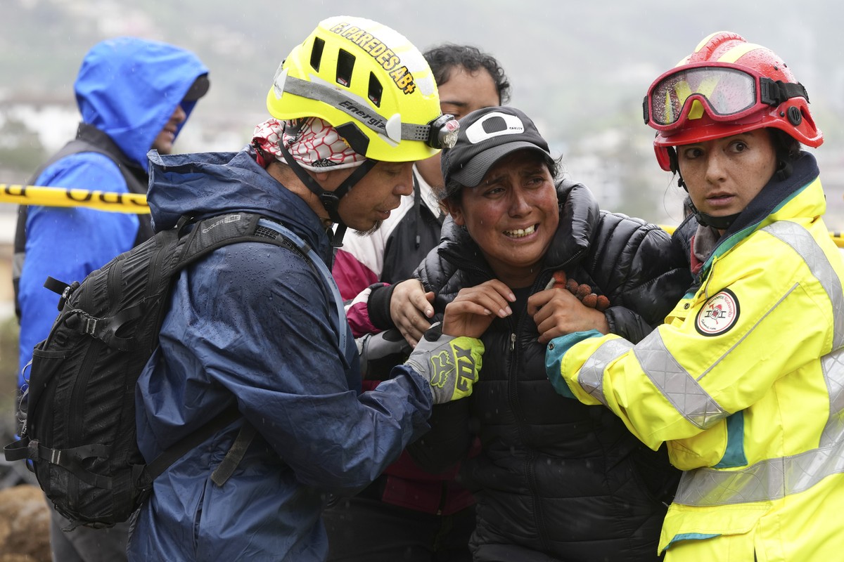 Des secouristes réconfortent une femme dont la fille a disparu pendant le glissement de terrain.