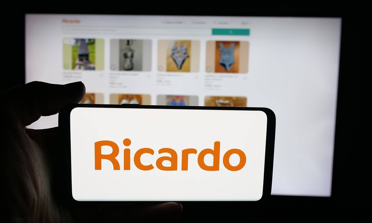 Illustration photos in Germany - 9 Oct 2025 In this photo illustration, a person is holding a cellphone with the logo of marketplace company Ricardo Ricardo.ch on screen in front of webpage. Germany C ...