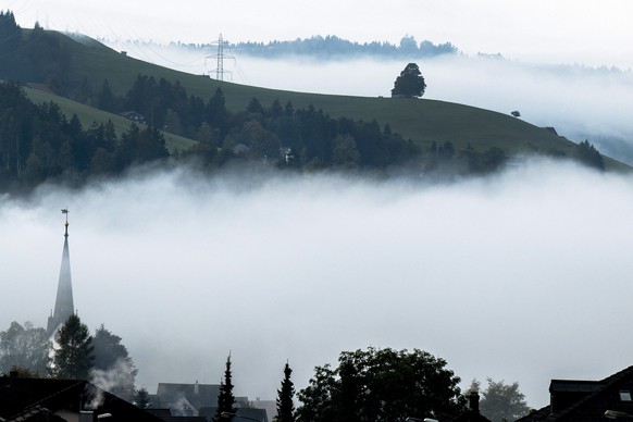 Der Kirchturm zeichnet sich durch den Nebel, am Montag, 16. Oktober 2023, in Wald. (KEYSTONE/Peter Schneider)