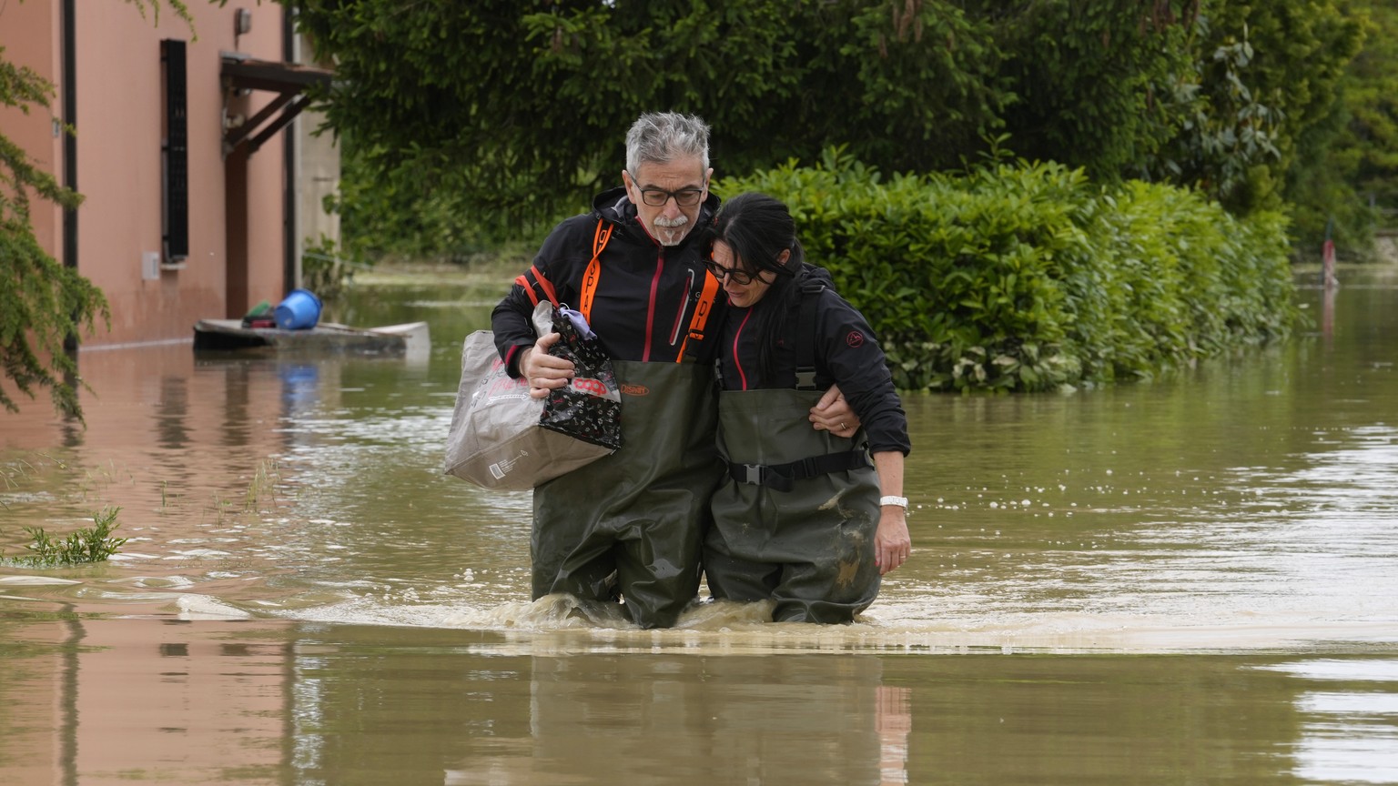 FILE - A couple walk through a flooded road of Lugo, Italy, May 18, 2023. The floods that sent rivers of mud tearing through towns in Italy?s northeast are another soggy dose of climate change&#039;s  ...