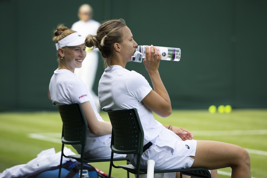 Celine Naef of Switzerland, back, and Viktorija Golubic of Switzerland take a break during a training session the All England Lawn Tennis Championships in Wimbledon, London, Saturday, July 1, 2023. Th ...