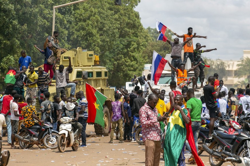 Supporters of Capt. Ibrahim Traore cheer with Russian flags in the streets of Ouagadougou, Burkina Faso, Sunday, Oct. 2, 2022. Burkina Faso's new junta leadership is calling for calm after the French  ...