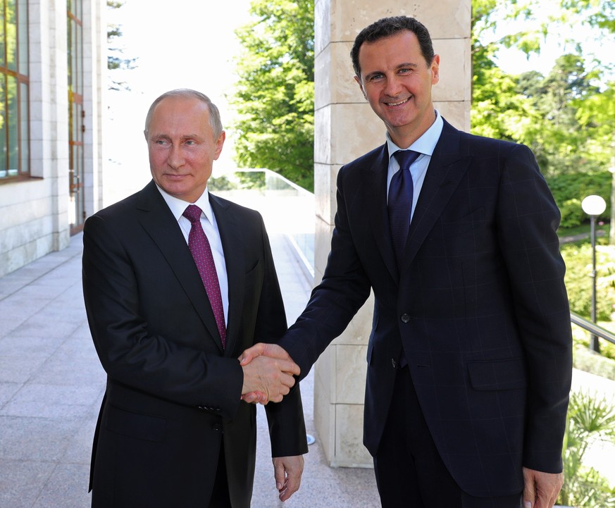 FILE - In this May 17, 2018, file photo, Russian President Vladimir Putin, left, shakes hands with Syrian President Bashar al-Assad during their meeting in the Black Sea resort of Sochi, Russia. Assad ...