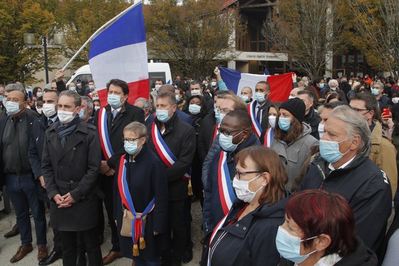 Local mayor Laurent Brosse, third left, and deputy mayors sing the national anthem outside the school where a slain history teacher was working, Saturday, Oct. 17, 2020 in Conflans-Sainte-Honorine, no ...