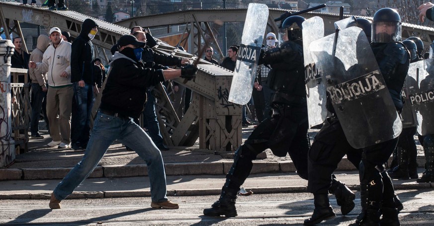 Ein Demonstrant schlägt bei einem Protest gegen die soziale Ungleichheit in Sarajevo auf Polizisten ein.&nbsp;
