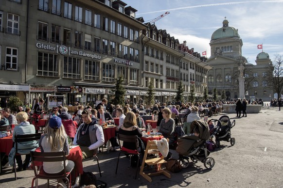 Sonnenhungrige geniessen das warme Fruehlingswetter an der "Front" vor dem Hintergrund des Bundeshauses am Donnerstag, 23. Februar 2017, in Bern. (KEYSTONE/Lukas Lehmann)