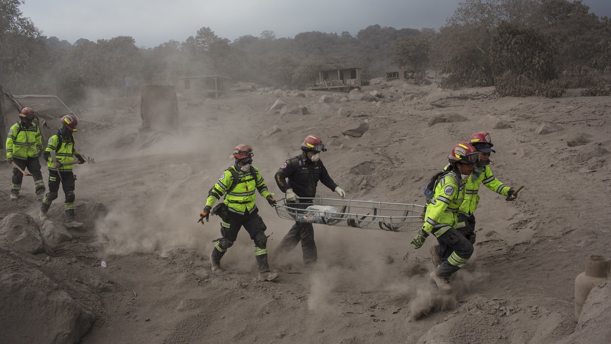 Rescue workers run for cover as the Volcan de Fuego, or "Volcano of Fire," blows more clouds of ash in the El Rodeo hamlet of Escuintla, Guatemala, Tuesday, June 5, 2018. The fiery volcanic  ...
