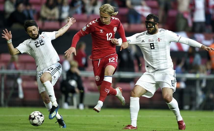 Denmark&#039;s Kasper Dolberg, centre, vies with Georgia&#039;s Gija Grigalova, right, and Giorgi Navalovski, during their Euro 2020 qualifier soccer match in Telia Parken, Copenhagen, Denmark, Monday ...