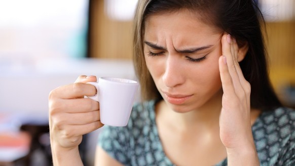 Frau mit Kaffee, Kopfschmerzen (Symbolbild)