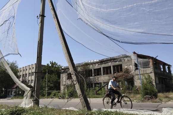 In this photo provided by Ukraine&#039;s 65th Mechanized Brigade press service, a local resident rides a bike along the street under an anti-drone net in Orikhiv, Zaporizhzhia region, Ukraine, Tuesday ...