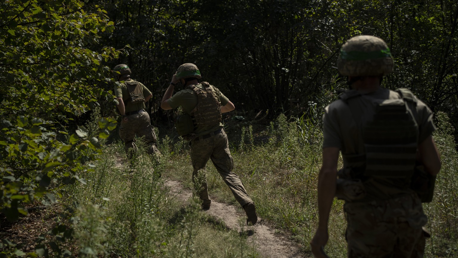 Ukrainian soldiers run towards a mortar position on the frontline in the outskirts of Kreminna, Ukraine, Wednesday, Aug. 16, 2023. (AP Photo/Bram Janssen)