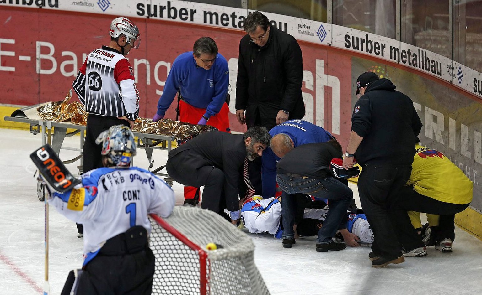 HC Fribourg-Gotteron Verteidiger Marc Abplanalp, am Boden, wird gepflegt u.a. von ZSC Team Arzt Dr. med. Gery Buesser, Vollbart, und spaeter abtransportiert im vierten Playoff-Halbfinalspiel der Natio ...