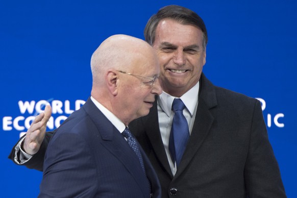 Brazil&#039;s President Jair Bolsonaro, right, leaves the stage next to German Klaus Schwab, left, Founder and Executive Chairman of the World Economic Forum, WEF, after a plenary session in the Congr ...