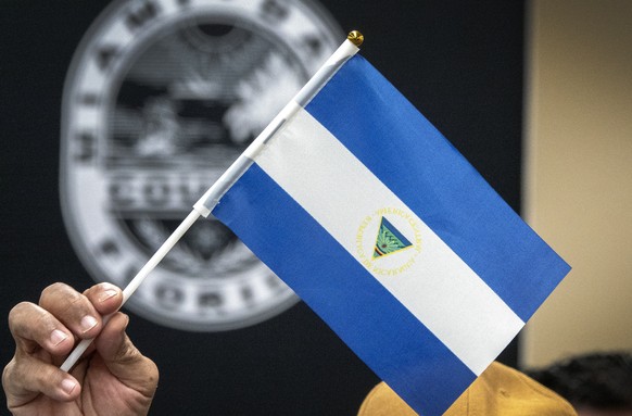 epa10468830 Nicaraguan ex-convict Victor Manuel Sosa Herrera holds an inverted Nicaragua flag during a press conference at the Stephen P. Clark Government Center in Miami, Florida, U.S., February 15, 2...