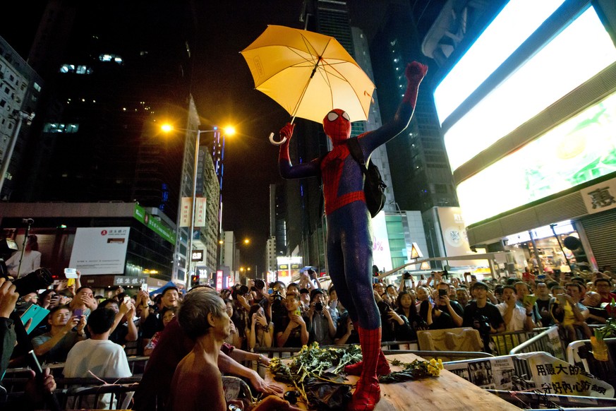A pro-democracy protester dressed as Spider-man, holding a yellow umbrella, stands on a barricade in the occupied area in the Mong Kok district of Hong Kong, Friday, Oct. 24, 2014. Pro-democracy prote ...