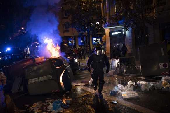 Police officers run past barricades during clashes with demonstrators following a protest condemning the arrest of rap singer Pablo Hasélin Barcelona, Spain, Saturday, Feb. 20, 2021. A fifth night of  ...