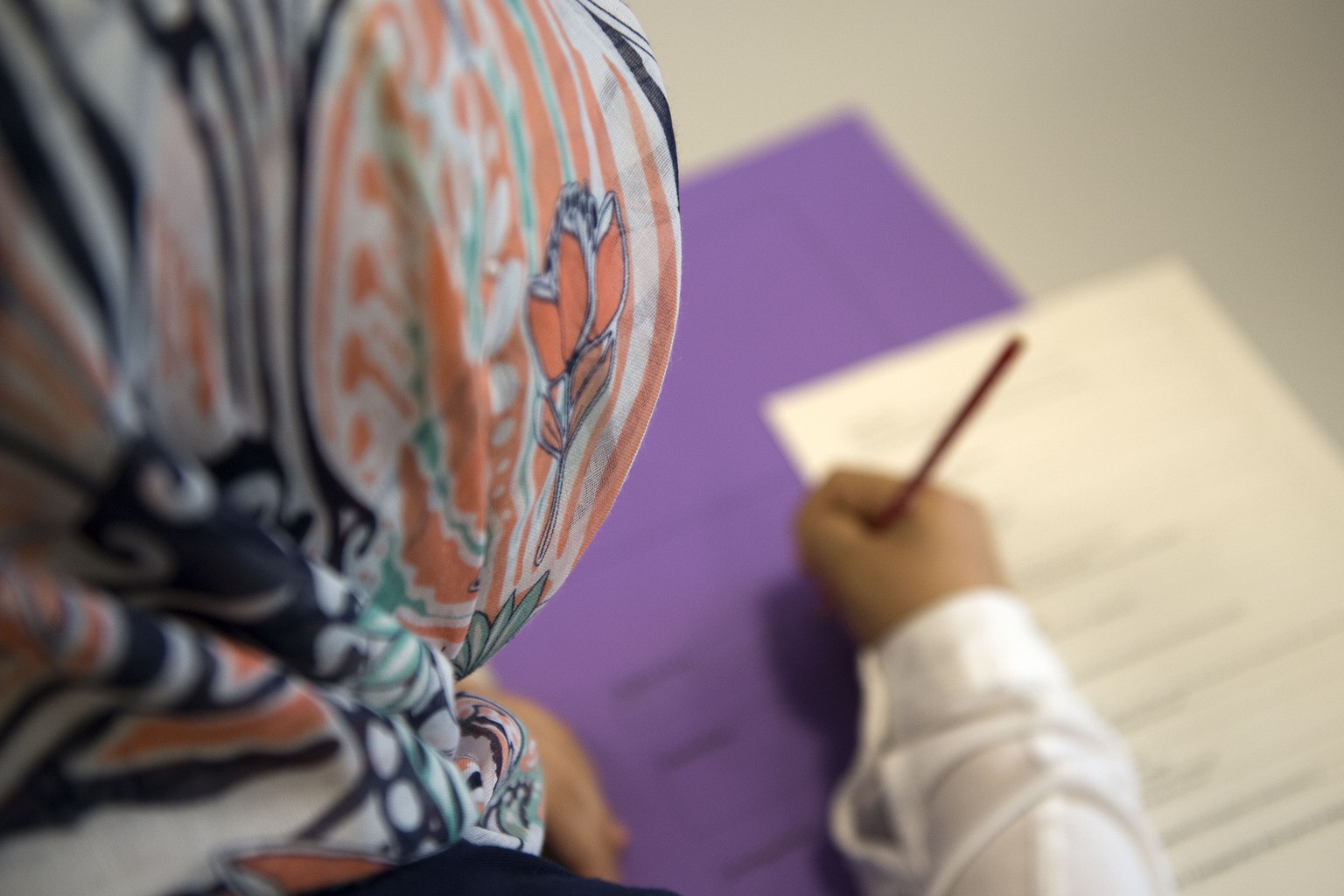 Eine Schuelerin mit einem Kopftuch schreibt in der Sekundarschule Theobald Baerwart in Basel am Montag, 17. August 2015. Die neue Sekundarschule nimmt an zehn Standorten in der Stadt ihren Betrieb auf ...