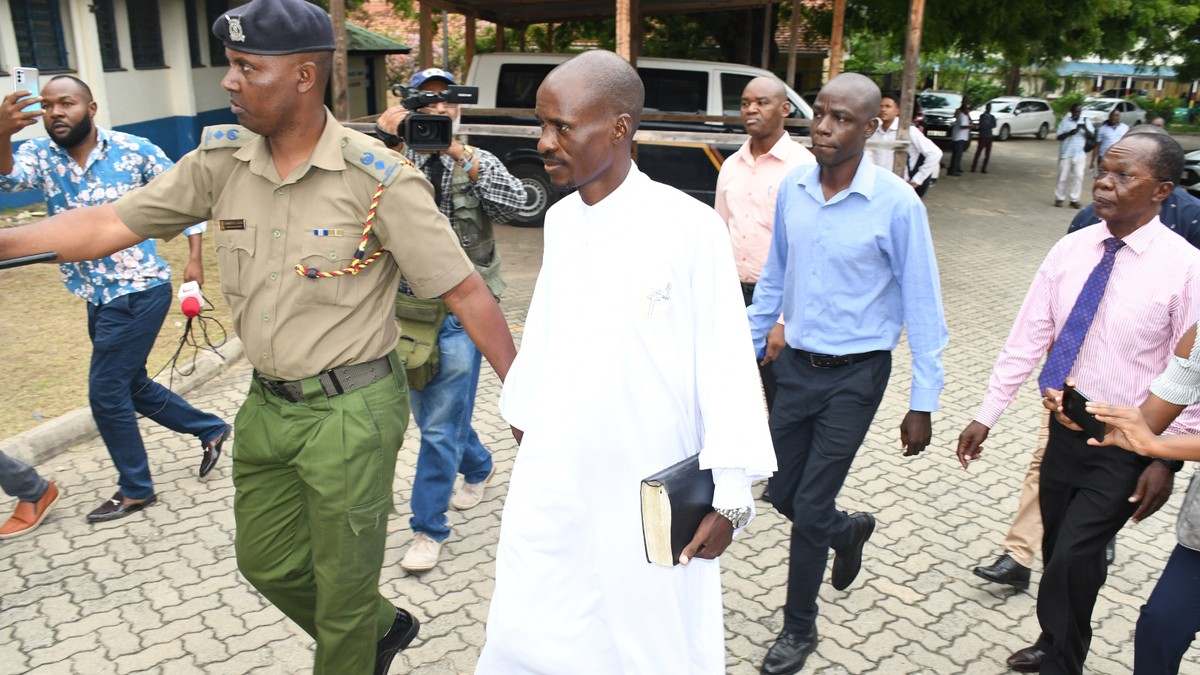 Pastor Ezekiel Odero, center, holds a bible as he is led by police in Mombasa, Kenya, Thursday April 27, 2023. Police in Kenya arrested another popular pastor on the Indian Ocean coast as the number o ...