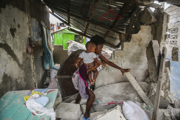 A woman carries her child as she walks in the remains of her home destroyed by Saturday� ?s 7.2 magnitude earthquake in Les Cayes, Haiti, Sunday, Aug. 15, 2021. (AP Photo/Joseph Odelyn)