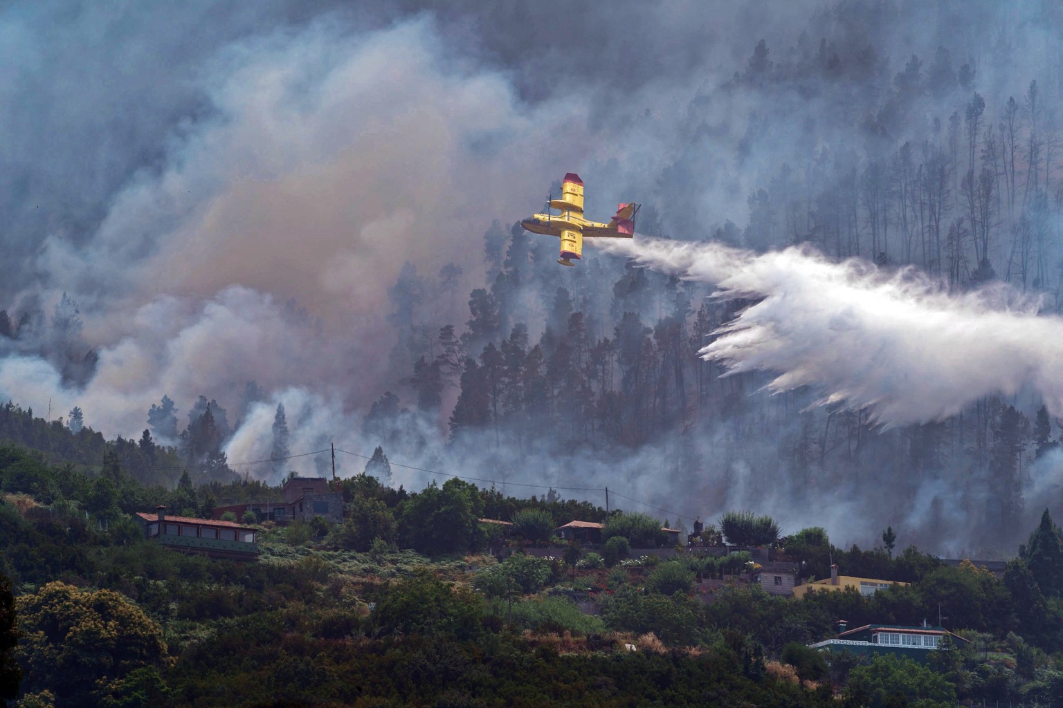 epa10087939 A hydroplane pours water into the forest fire in La Orotava, Tenerife, Canary Island, Spain, 23 July 2022. The forest fire started on 21 july and it has burnt 2.000 hectares. EPA/Ramon de  ...