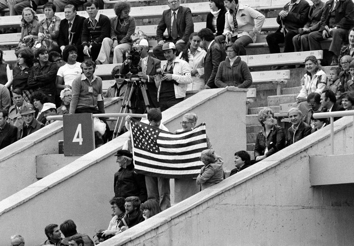 Three unidentified people display an American flag in the stands at Moscow's Lenin Stadium before the start of opening ceremonies of the XXII Summer Olympics, July 19, 1980. Officials estimate ab ...