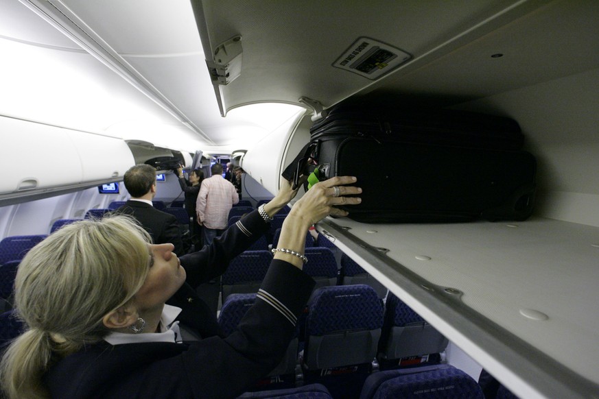 FILE - In this April 13, 2009 file photo, American Airlines flight attendant Renee Schexnaildre demonstrates the overhead baggage area during a media preview of the airline&#039;s new Boeing 737-800 j ...