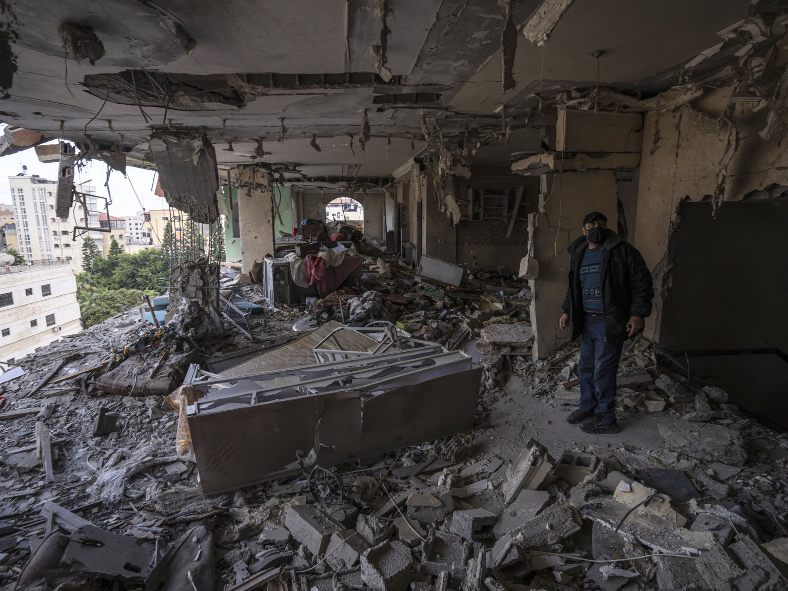 A Palestinian man inspects damage to his building after Israeli air strikes on an apartment belonging to an Islamic Jihad commander in Gaza City, Tuesday, May 9, 2023. The Israeli army says it has killed ...