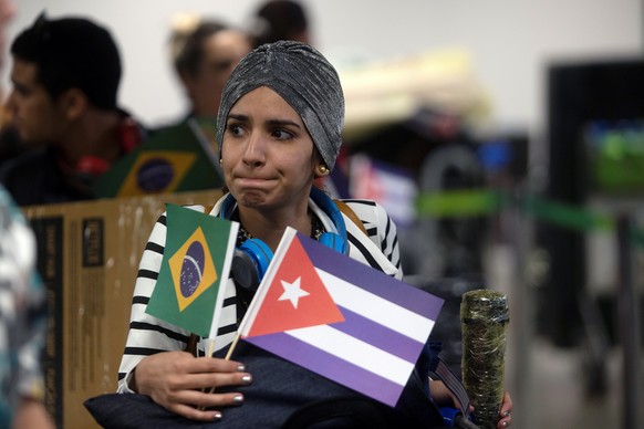 epa07183656 A person holds flags as doctors of the &#039;Mais Medicos&#039; (More Doctors) program prepare to depart Brazil at the Brasília International Airport in Brasilia, Brazil, 22 November 2018. ...