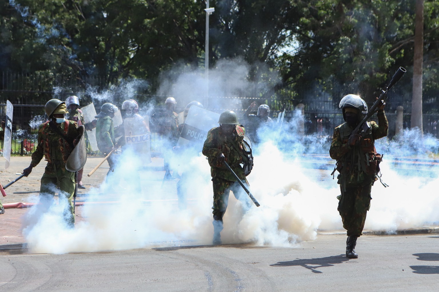 epa11437047 Armed members of the Kenyan security forces fire teargas at demonstrators during a protest near the Parliament against tax hikes, in Nairobi, Kenya, 25 June 2024. Protesters have breached  ...