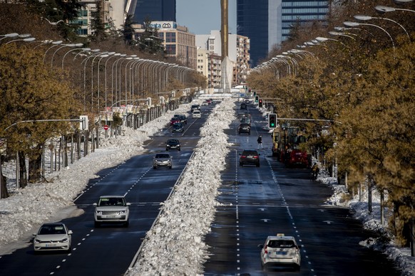 Cars circulate along Paseo Castellana covered with the snow in Madrid, Spain, Monday, Jan. 11, 2021. The Spanish capital is trying to get back on its feet after a 50-year record snowfall that paralyzed large parts of central Spain over the weekend. (AP Photo/Manu Fernandez)