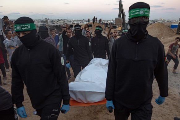 epaselect epa12487945 Hamas militants carry a white bag containing a body after retrieving it from a tunnel in Khan Yunis, southern Gaza, 28 October 2025. The retrieval is part of an ongoing operation ...