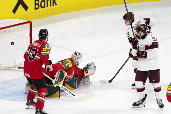 Latvia's Sandis Vilmanis, top right, scores the eighth goal against Hungary's Milan Horvathand Hungary's goaltender Bence Balizs, left, during the 2026 IIHF Men's Ice Hockey World  ...