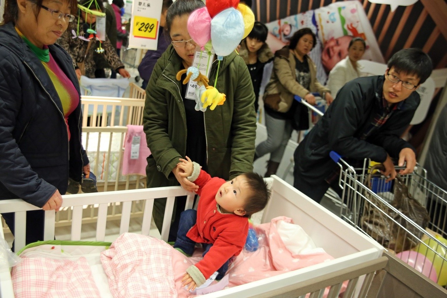 A Chinese baby plays in a bed at a flatpack furniture store in Shenyang city, China&#039;s Liaoning province, 16 November 2013. China plans to loosen its &#039;one child&#039; family planning policy,  ...