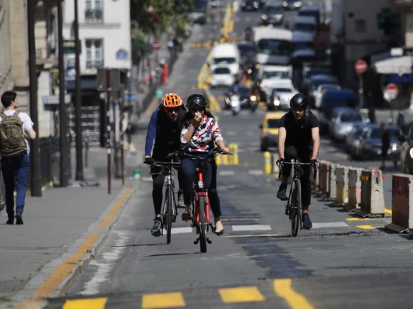 People ride on the new bike lanes Thursday, May 7, 2020 in Paris. The French capital enlarged bicycles lanes, shown with yellow painting, as it prepares the end of lockdown next Monday. For now, Franc ...