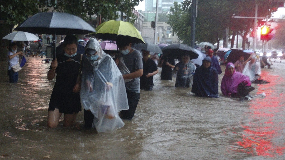 People move through flood water after a heavy downpour in Zhengzhou city, central China's Henan province on Tuesday, July 20, 2021. Heavy flooding has hit central China following unusually heavy  ...