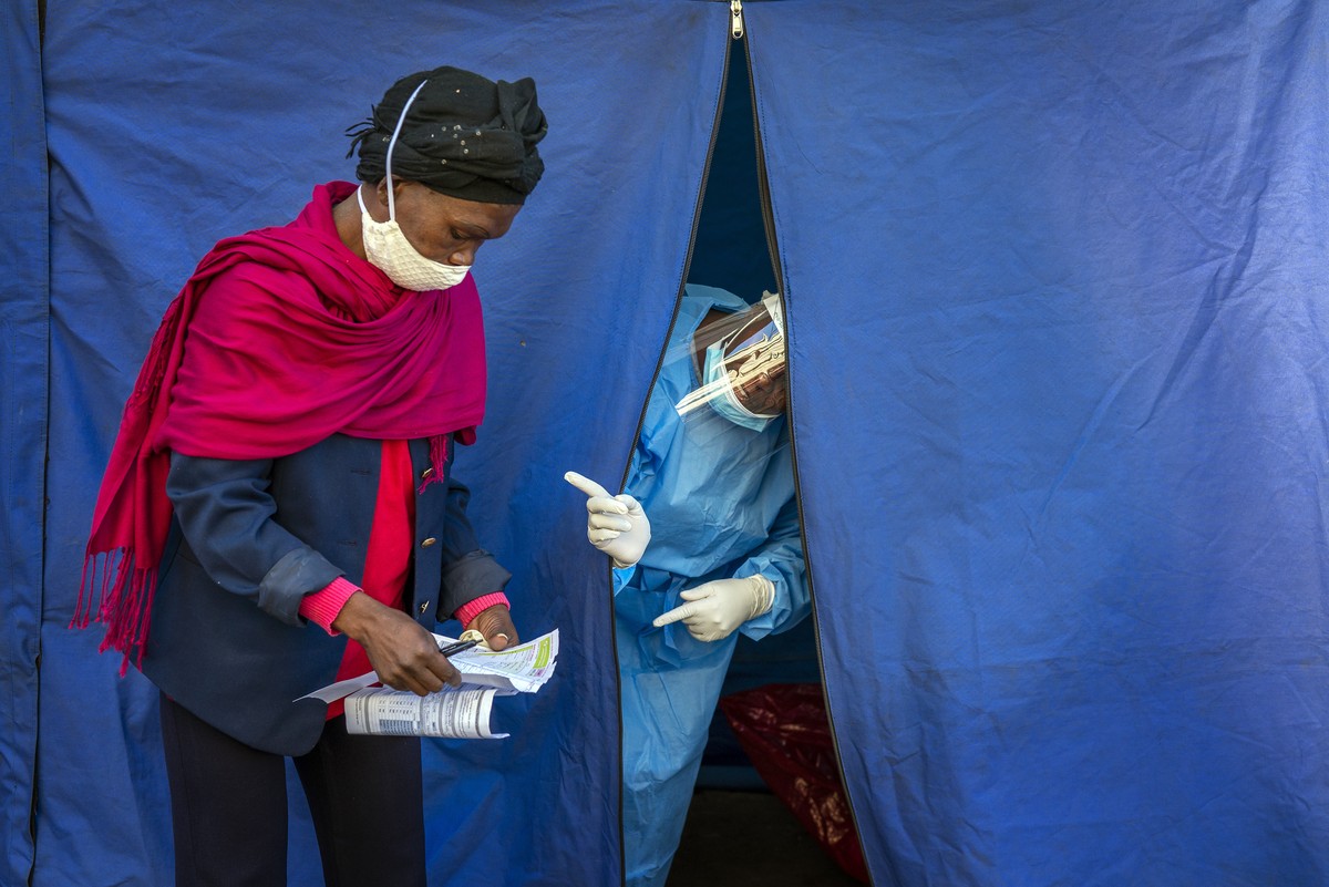 Heath officials check the listings of people who are to be tested for COVID-19 as well as HIV and Tuberculosis, in downtown Johannesburg Thursday, April 30, 2020. Thousands are being tested in an effo ...