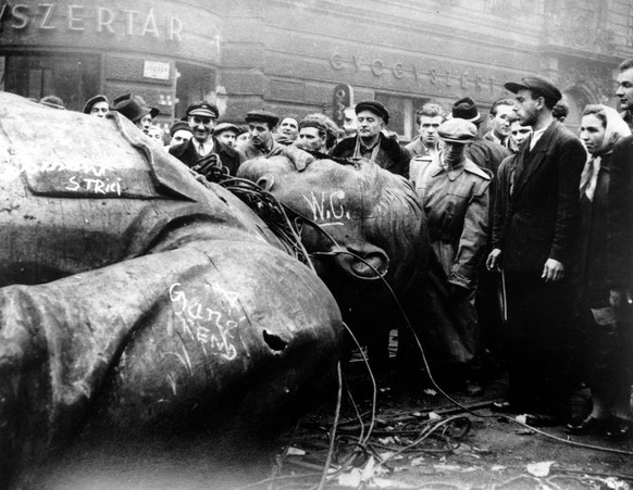 Hungarians witness the fallen statue of communist leader Josef Stalin in front of the National Theater in Budapest on October 24, 1956. Demonstrators revolting against communist rule in Hungary pulled ...
