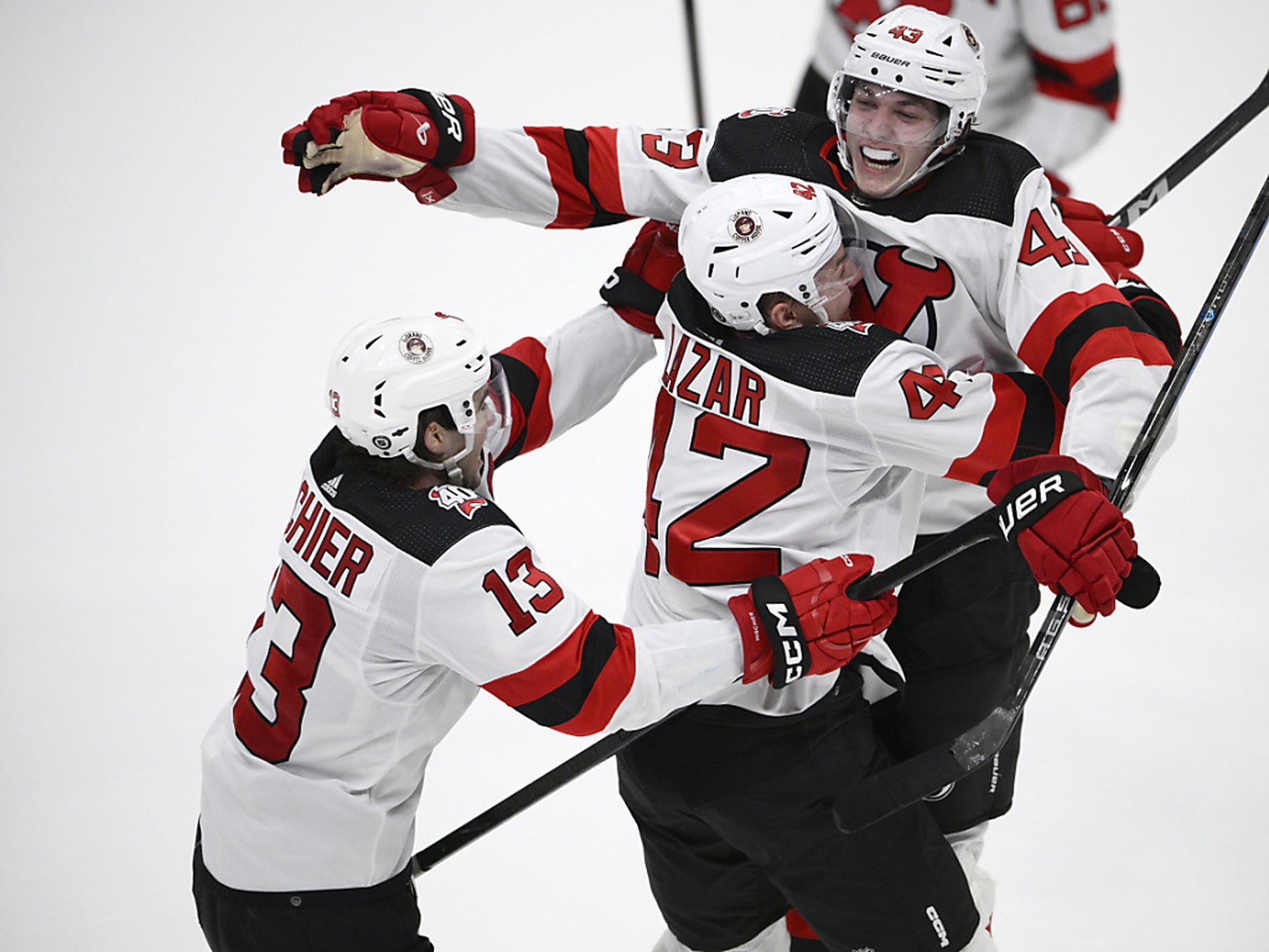 Nico Hischier (� gauche) et Curtis Lazar f�tent Luke Hughes apr�s son but qui donne la victoire � New Jersey.