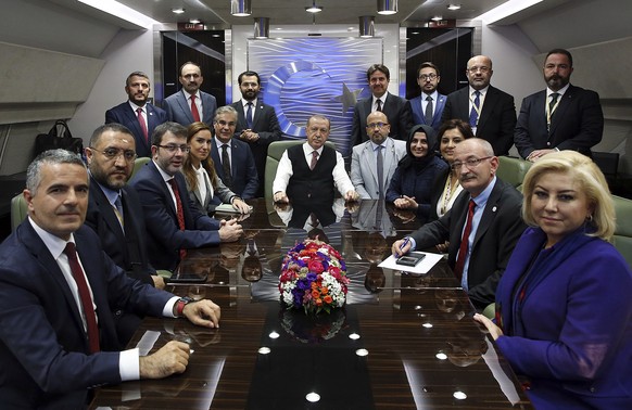 Turkey&#039;s President Recep Tayyip Erdogan, center, poses inside his plane for a photo with journalists traveling with him back from a state visit to Hungary, late Wednesday, Oct. 10, 2018. Erdogan  ...