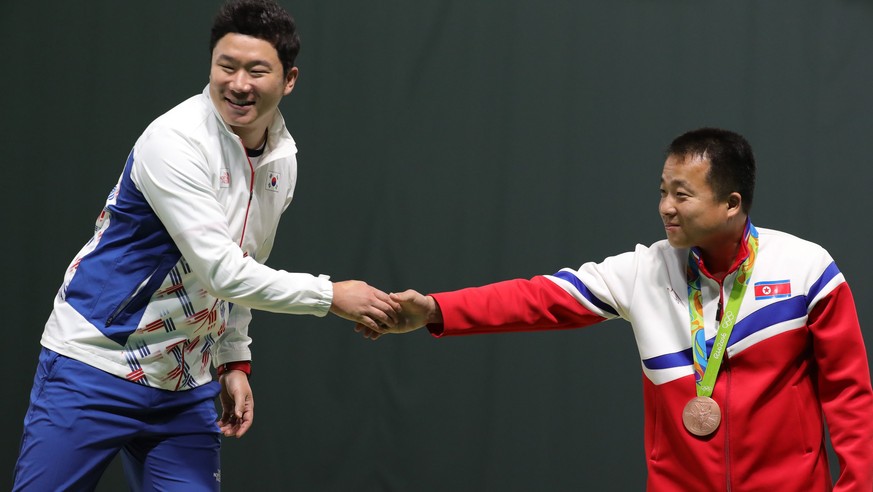 epa05470800 Gold medal winner Jin Jongoh (L) of South Korea shakes hand with bronze medal winner Song Guk Kim of North Korea on the podium of the men&#039;s 50m Pistol competition of the Rio 2016 Olym ...