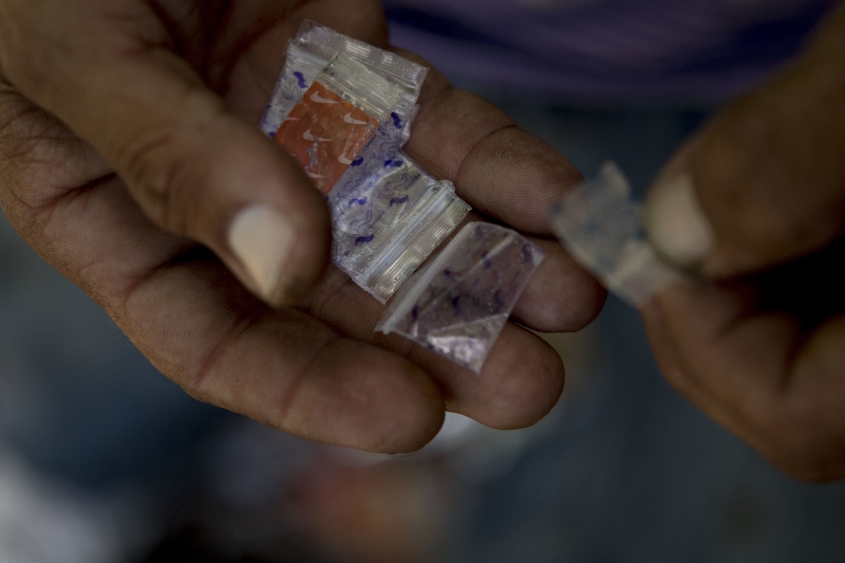 In this Dec. 14, 2018 photo, a heroin user gives empty heroin bags to a member of the "Intercambios Puerto Rico" needle exchange program to be tested for fentanyl, after injecting heroin int ...