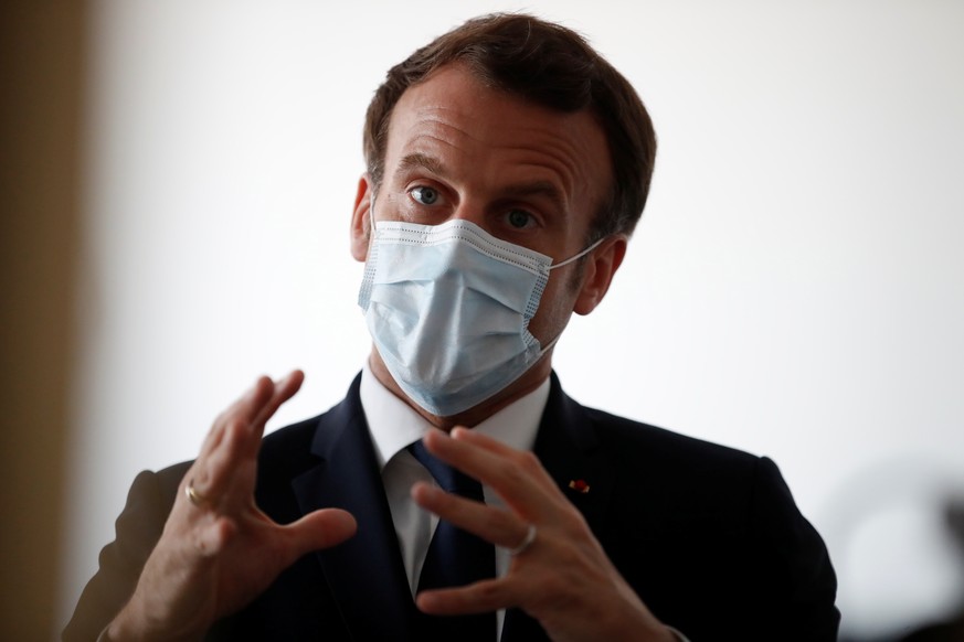 epa08348358 French President Emmanuel Macron, wearing a protective face mask, talks with health workers as he visits a medical center in Pantin near Paris as the spread of the coronavirus disease (COV ...