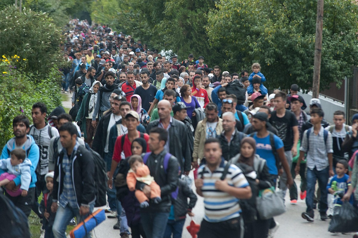 epa04930491 Migrants who had arrived from Roszke by train, walk toward Austria in Hegyeshalom, 168 kilometers west from Budapest, Hungary, 14 September 2015. Thousands of migrants were rushing to reac ...