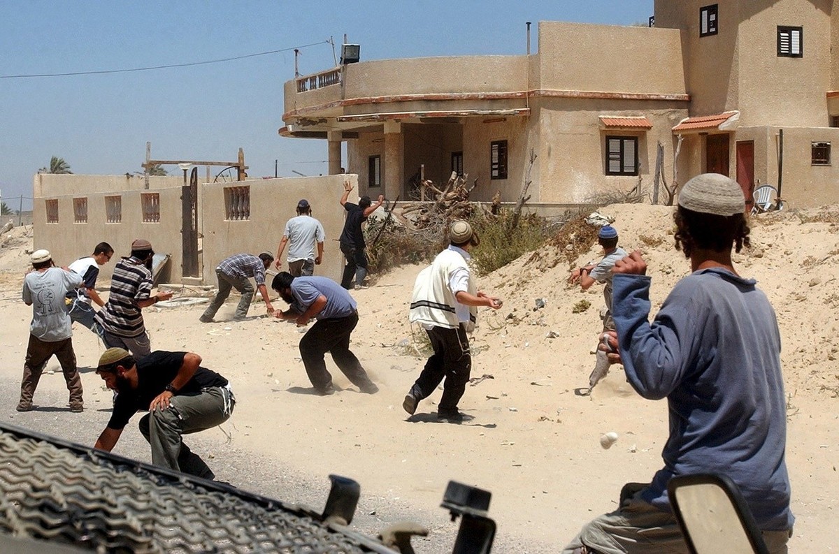 Jewish settler throw stones at a Palestinian house next to the Palestinian house in the Muazzi area of the southern Gaza Strip that settlers yesterday occupied and are refusing to leave on Wednesday,  ...