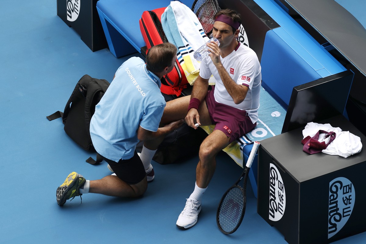 Switzerland's Roger Federer receives treatment from a trainer during his quarterfinal against Tennys Sandgren of the U.S. at the Australian Open tennis championship in Melbourne, Australia, Tuesd ...