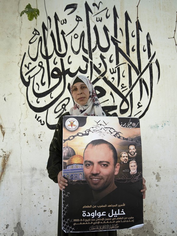 Palestinian Dalal Awawdeh poses with a poster of her husband Khalil Awawdeh, who is a prisoner in Israel, at the family house, in the West Bank village of Idna, Hebron, Tuesday, Aug. 9, 2022. Awawdeh, ...